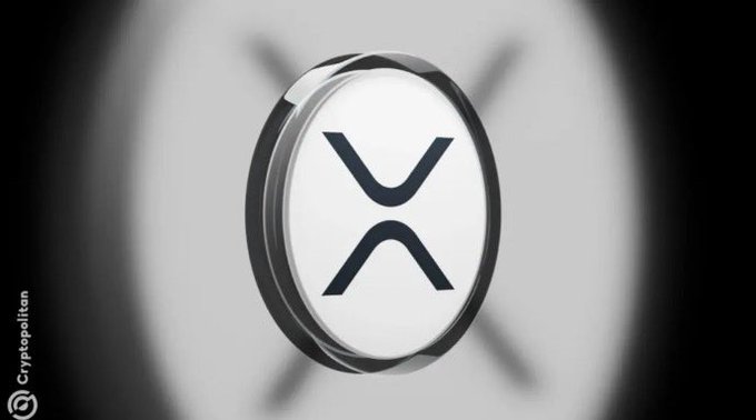 A stylized 3D rendering of the XRP cryptocurrency logo (the stylized X symbol) by Cryptopolitan, displayed on a metallic circular coin against a blurred background.