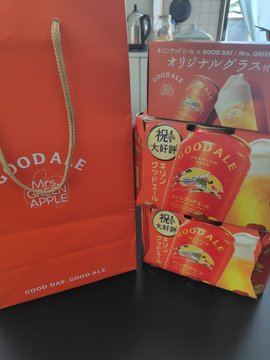 A photo of a red Gooday GOLD MEDAL APPLE branded paper bag alongside two boxes of Gooday Original Granola with apple slices, a Japanese snack product.