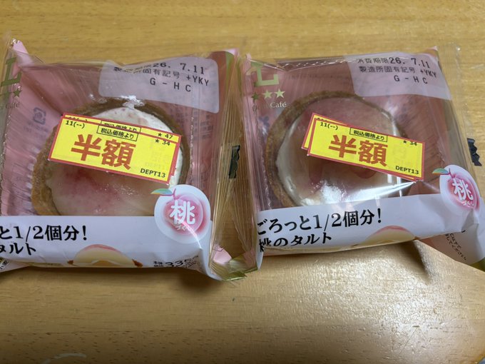 Two packaged Japanese peach tarts are displayed on a wooden surface, with labels indicating '半額' (half price) and a best-by date of 26.7.11.