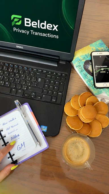 A woman holds open a planner reading "New week's start: record in Beldex GM" beside a Dell laptop displaying the Beldex "Privacy Transactions" logo, a stack of mini pancakes, and a coffee on a wooden desk, visually reinforcing the post's Monday morning shoutout to Beldex's privacy-focused tools.