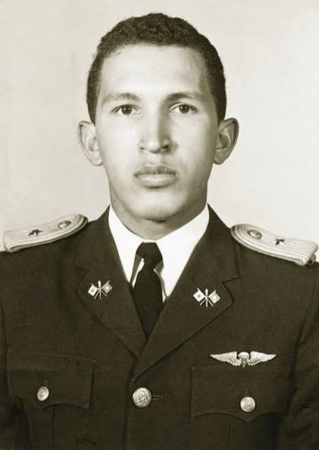 A sepia-toned portrait of a young man in a dark military uniform. He wears shoulder boards with star insignia, collar insignia, and a winged badge on his chest.