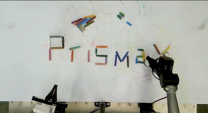 A robotic arm uses colored markers to spell out "PRISMAX" on a whiteboard, visually reinforcing the post's discussion of the @PrismaXai decentralized data network by literally constructing the project's name through automated precision.