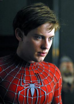 A close-up of Tobey Maguire in his iconic red and black Spider-Man suit with the web-patterned design. The image visually supports the post about his anticipated return as Spider-Man in the upcoming Marvel film.