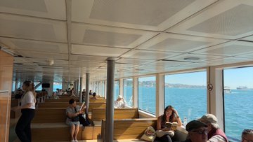 The image shows a group of people sitting together inside a boat, enjoying their time on the water. There are at least nine people visible in the scene, with some seated on benches while others stand or sit on chairs. The boat appears to be a cruise ship, as it is filled with passengers and has multiple seating areas for them to relax in. The post accompanying this image provides information about the location of the boat and its passengers, possibly including details such as their names, ages, and genders.