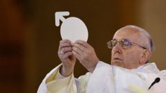 Pope Francis holds up the white Eucharistic host during a religious ceremony.
