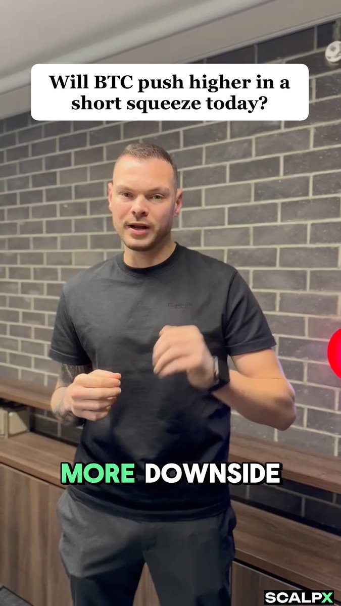 A man in a black t-shirt stands in front of a brick wall addressing the camera about Bitcoin's price movement, with the question "Will BTC push higher in a short squeeze today?" displayed above and the answer "MORE DOWNSIDE" highlighted in green at the bottom, alongside the ScalpX branding.