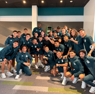 A sports team in dark teal uniforms poses together for a group photo indoors, holding a trophy. The image connects to the post as a celebratory moment suggesting a winning bet, likely tied to the World Cup excitement and Roobet's betting odds mentioned.