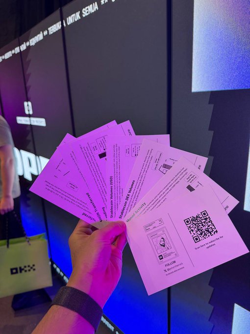A hand holding four pink tickets with QR codes for a 'SHINee World VI' concert, with an 'OKX' branded bag visible in the background.