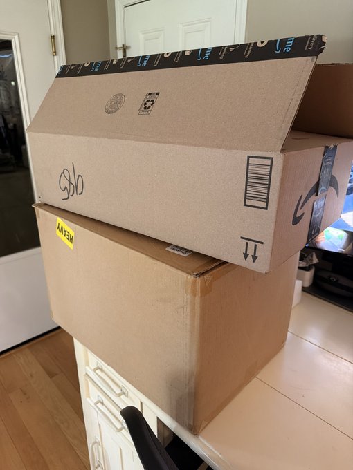 Two stacked cardboard boxes sitting on a kitchen counter, one appearing to be an Amazon package.