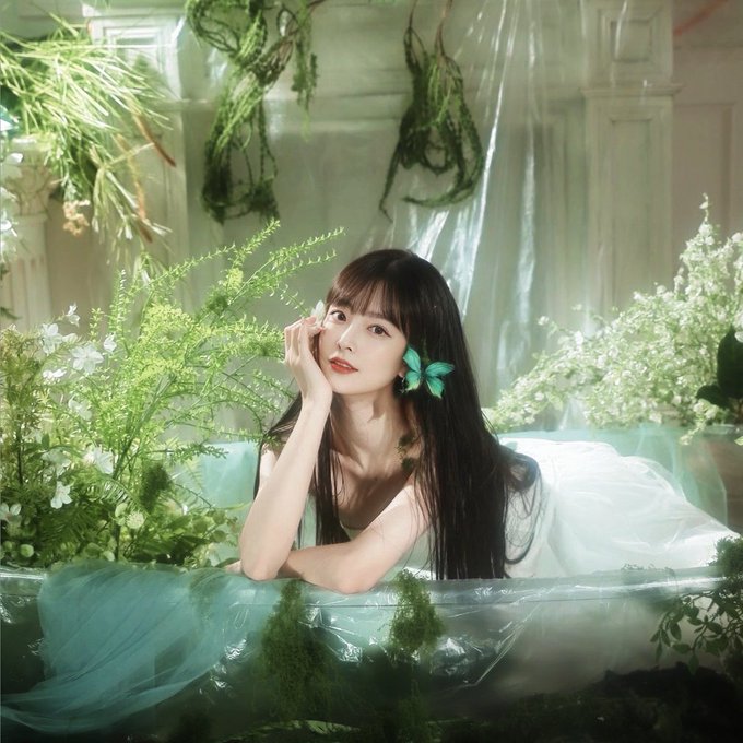 The image features a woman with long hair, likely an Asian lady, resting in a tub surrounded by flowers and plants. She appears to be posing for a picture, with her hand resting on her face as she looks directly at the camera. The backdrop of the scene is filled with greenery, creating a beautiful and serene atmosphere.

The post discussing this image is from @quipnetwork's account, which has been described as follows: "This isn't about you... it's about them!". A summary of the image, including its main focus on a woman in a floral-filled bathtub, can be found at the bottom right corner.