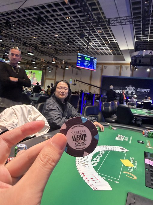 A poker player holds up a Caesars/WSOP chip ($66,000) at the felt during the WSOP at Paris Las Vegas, their round shape and high denomination evoking the distinctive design of Aria baccarat chips.