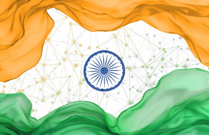 A digital illustration of the Indian national flag, with its saffron, white, and green colors rendered in a flowing, smoky texture, featuring the blue Ashoka Chakra wheel at the center against a background of connected network nodes.