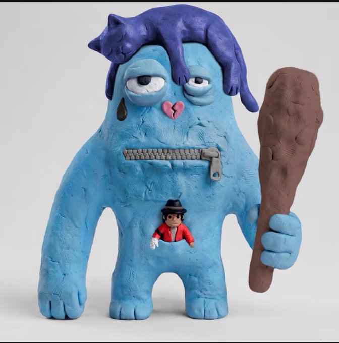 A hand-sculpted clay figure of a blue monster-like character with purple hair, holding a brown club, featuring a zipper mouth and a small figure in a red jacket and hat emerging from its chest pocket.