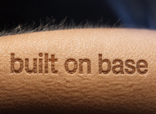 The image features a close-up of someone's arm with the words "built on base" written on their skin, likely as part of a tattoo or other body art. The text is clearly visible against the person's skin tone, making it an interesting visual element in the photo.