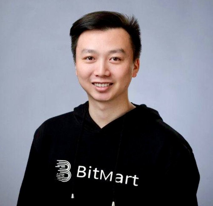Portrait photo of a smiling man wearing a black BitMart hoodie against a grey background.