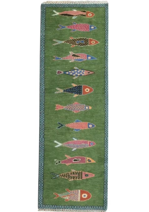 A green woven rug featuring a vertical row of stylized colorful fish designs.