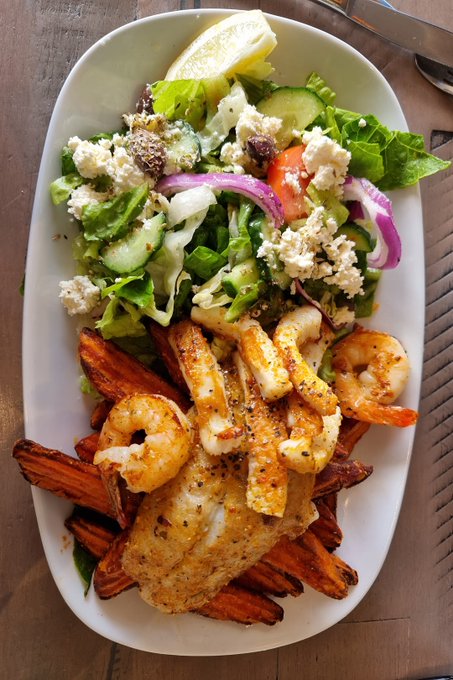 The image shows a white plate containing a delicious seafood dish, consisting of a grilled fish fillet along with some sweet potatoes. The combination of these ingredients creates an appetizing and visually appealing meal that could be considered worth waiting for due to its presentation and quality. The accompanying post promotes the meal as a must-see and worth a wait in line for, suggesting it's likely a high-quality dish offered at this location or restaurant.