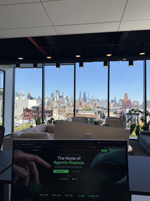 A view from a modern high-rise office with floor-to-ceiling windows overlooking the New York City skyline, featuring a Dell monitor and an open laptop displaying a webpage titled 'The Home of Agentic Finance' on a dark-themed site.