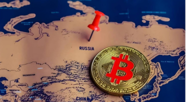 Photograph of a gold Bitcoin coin placed on a map near a red pushpin marking Russia, with China visible to the south.