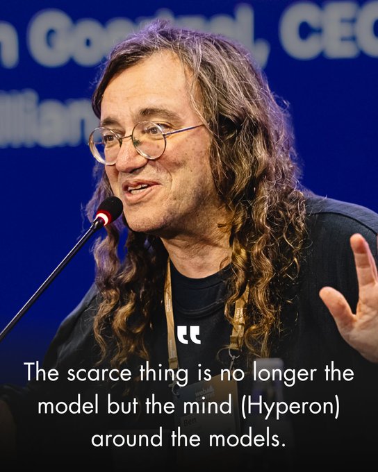 A speaker with long curly hair and round glasses addresses an audience at a podium with a microphone, set against a blue backdrop displaying partial text including "Goodall" and "CEO." A quote overlay reads: "The scarce thing is no longer the model but the mind (Hyperon) around the models." The caption "bengoertzel" is also visible, suggesting the speaker is Ben Goertzel.

The image aligns with the post, which highlights Dr. Ben Goertzel discussing Kimi K3 and emphasizing that future AI value lies not in the models themselves but in the surrounding cognitive frameworks, much like Hyperon.