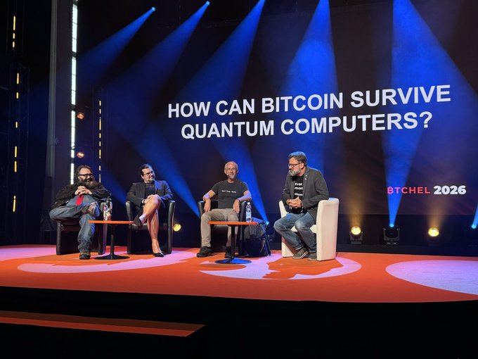 A panel discussion on a stage with the text 'HOW CAN BITCOIN SURVIVE QUANTUM COMPUTERS?' and 'BTCHEL 2026' displayed on the large screen behind four seated speakers.