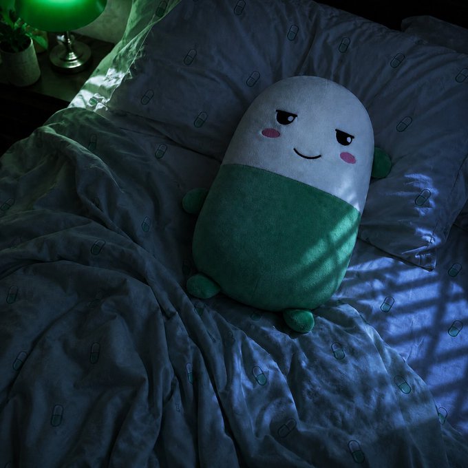 A sleepy-eyed cup-and-pill plushie rests against pillows on a bed, with a green nightlight glowing softly in the corner—mirroring the post's playful mention of $CUPSEY, "the cute little pill," looking drowsy as if bracing for its "next leg" rally.