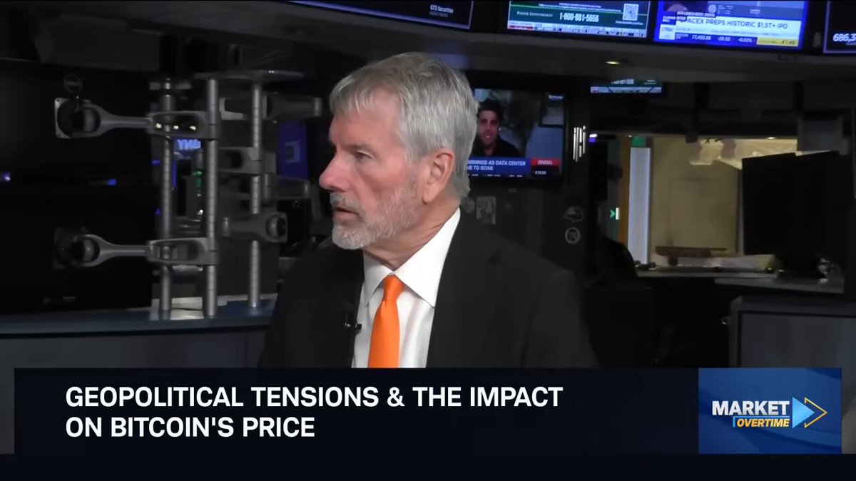 The image features an older man wearing a suit and tie, standing behind a desk with a computer monitor in front of him. The text "Geopolitical tensions & the impact" can be seen above his head, while the words "Bitcoin sometimes feels like risk cubed." are written below his feet. This suggests that the man is discussing Bitcoin's impact on geopolitical tensions and how it affects the market.