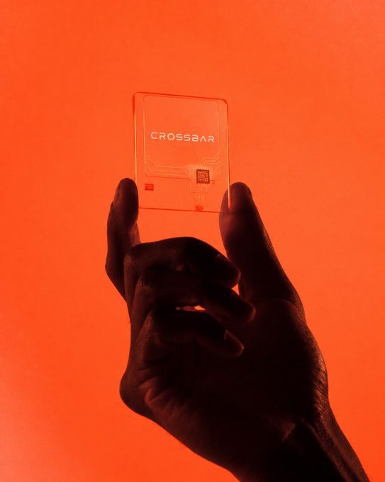 A silhouetted hand holds up a transparent card with the word "CROSSBAR" printed on it, set against a vibrant orange background.