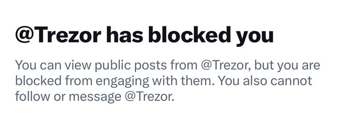 A screenshot of a social media notification stating '@Trezor has blocked you', explaining that public posts can be viewed but engagement is restricted.