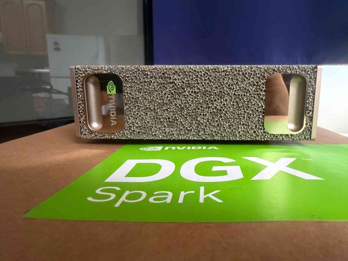 A textured silver metal enclosure, possibly a cooling block or graphics card cover, sits on top of a green and brown cardboard box labeled 'NVIDIA DGX Spark'.