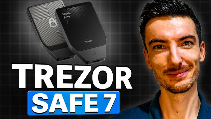 The image features a man smiling at the camera with the text "Trezor Safe 7" displayed above him, indicating that he is reviewing or discussing Trezor's new hardware wallet. The background of the image is black, which contrasts with the white text and makes it stand out.