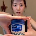 A close-up of a person holding up a small jar of Vaseline, with 'Vaseline' text displayed at the bottom of the frame.