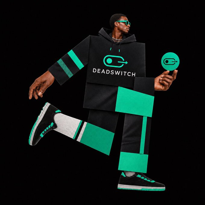 The image features a man dressed in a black and green outfit with white stripes, holding a green object in his hand. There are no other people or objects visible in the image. The focus of the image is on the man's attire and the green object he is holding.