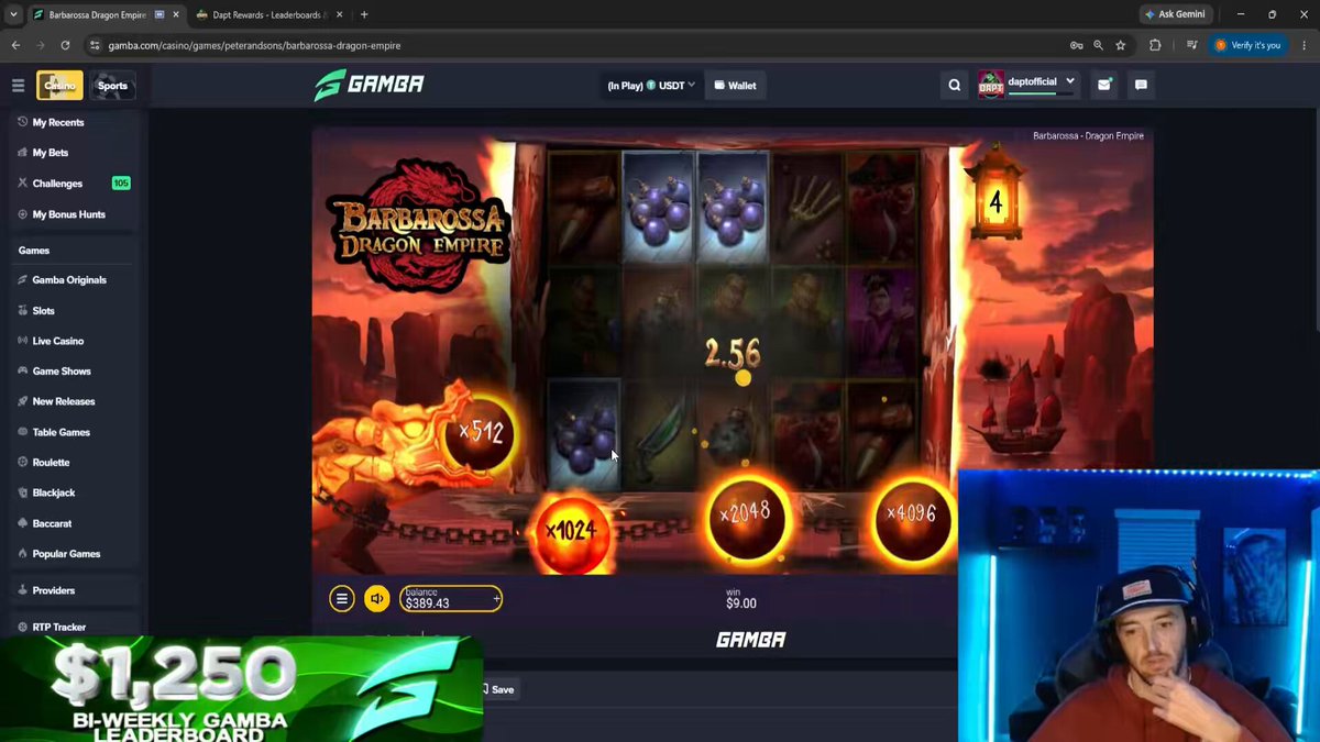 The image shows a computer screen displaying a slot machine game, possibly Gambia. The man sitting at the computer appears to be playing or controlling the balance of the game. He wears a red shirt while using his right hand. A large amount of money is involved in the game, as indicated by the amount displayed on the screen, which amounts to $1,500. Additionally, there are two green coins visible, possibly representing points that can be earned from playing the game.