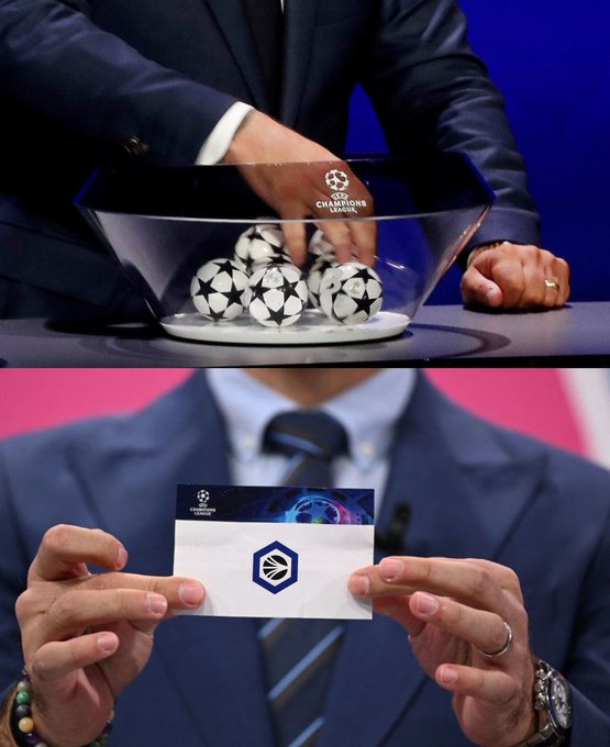 The image shows a UEFA Champions League draw ceremony, with officials handling branded balls in a glass bowl and displaying a team card in the bottom panel. The Champions League branding is visible on both the bowl and the card, though there's no direct connection to the cryptocurrency ticker mentioned.
