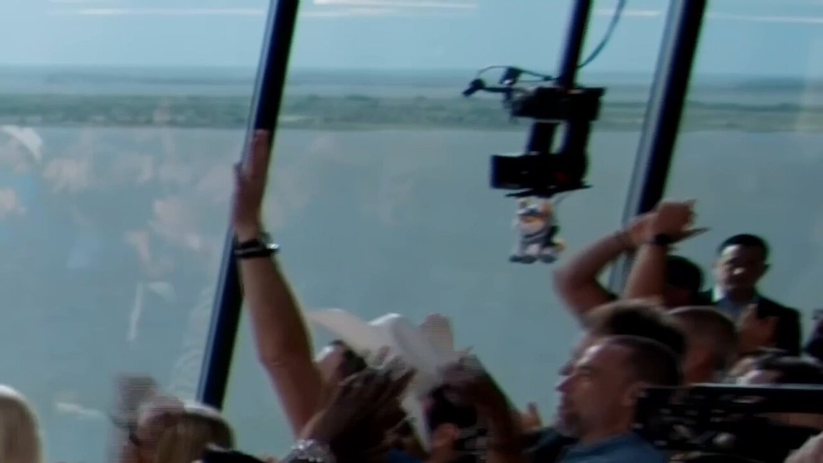 The image shows a group of people gathered together, with one person holding up their hand as if they are raising a flag or waving something. The scene takes place inside a building, possibly an office space or a meeting room, where several individuals can be seen in various positions around the room. There is also a large window visible in the image that provides a view of the sky outside.

The post on social media reads: "ASTEROID candles to 70M after being spotted in the SpaceX IPO day film Is it only a matter of time?". This suggests that there might be an event or celebration related to the launch of the Space Shuttle, and the post is likely meant to share this information with others.