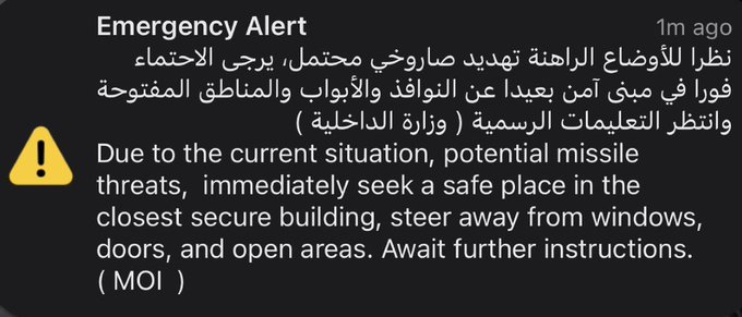 An emergency alert message in Arabic and English warning about 'potential missile threats' and advising people to seek shelter away from windows and open areas, issued by the MOI (Ministry of Interior) 1 minute ago.