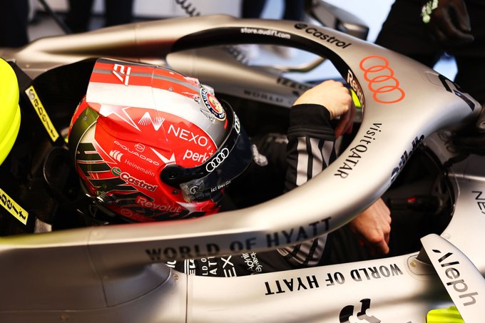 A race car driver in a red and silver helmet with "NEXO" and "Revolut" logos is seated in a car branded with "Audi" and "World of Hyatt," highlighting the urgency of the Nexo x Audi F1 partnership with the phrase "Every. Second. Counts."