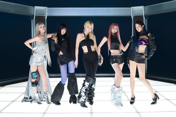 Five women in coordinated black and metallic futuristic outfits pose confidently on a glowing platform, showcasing a sleek, high-fashion aesthetic. The image appears to be a promotional or performance shot, likely from a K-pop group, contrasting the stylized glamour with the post's note about declining listenership on StationHead.
