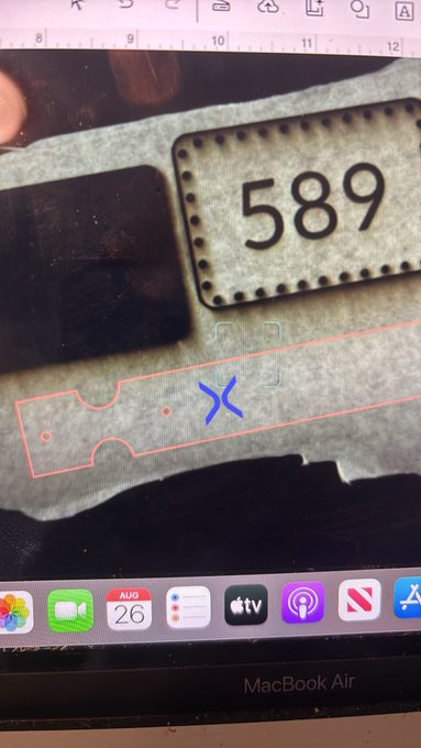A MacBook Air screen showing what appears to be a design or laser-cutting software with a tag labeled '589' and a ruler visible at the top.