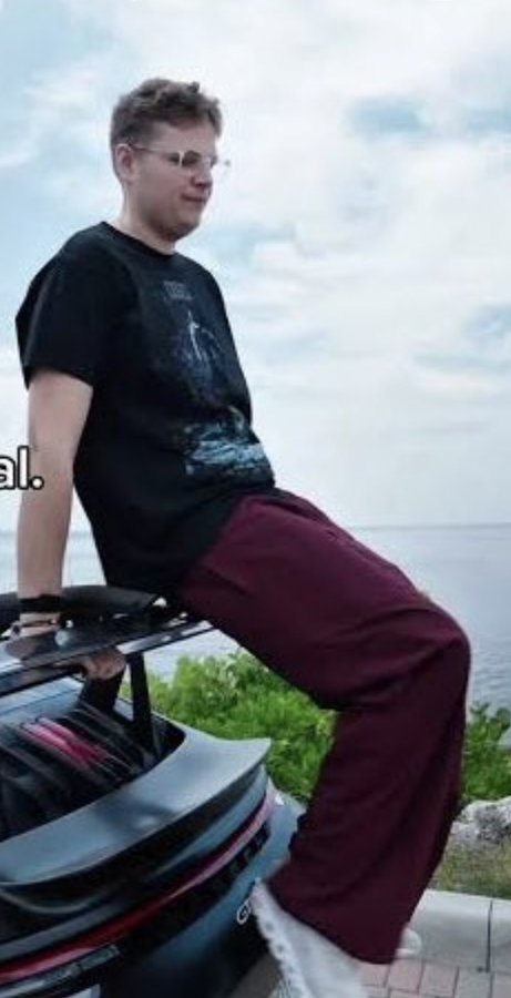 A man wearing glasses, a black T-shirt, burgundy pants, and white shoes leans against a jet ski near the water under a cloudy sky. The image appears to illustrate the post’s phrase, “I wanna be a Pump/FOMO KOL,” though no clear logo or other identifying text is visible.