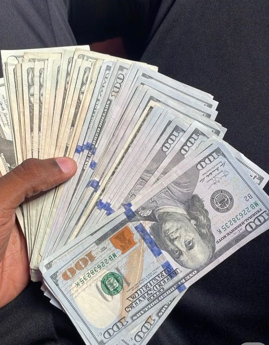 A hand fans out a thick stack of $100 bills, secured with blue currency straps, showing the serial number MB22230823R and "FEDERAL RESERVE NOTE" / "THE UNITED STATES OF AMERICA" text — inviting viewers to guess the total amount for a chance to win $50.