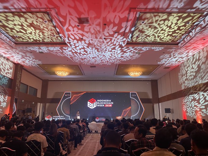 Crowd at Indonesia Blockchain Week 2026 conference, with attendees seated facing a stage featuring the event's logo under decorative ceiling projections.