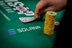 The image features a person's hand holding a green poker chip with the word "solana" written on it, which suggests that they are playing a game of poker involving the use of the Solana token as currency or a betting system. The person is likely using this token in combination with standard poker chips to create an interesting and unique gaming experience.
