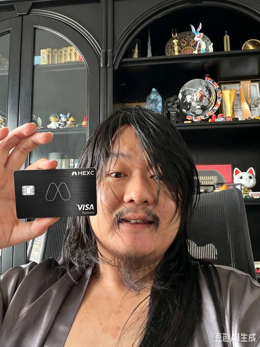 A man with long dark hair holds up a black "MEXC VISA Platinum" card toward the camera, standing in front of a shelf displaying various figurines, awards, and decorative items, visually promoting the MEXC Visa card mentioned in the accompanying post about still-functional crypto spending cards with 10% cashback and 7% APR earnings.