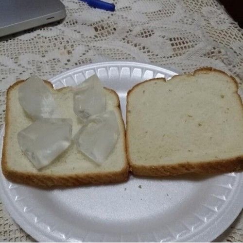 The image shows two pieces of bread with ice cubes placed on top, sitting on a white plate. The background appears to be a dining table or countertop covered with a lace doily patterned cloth. There are also some objects scattered around the table, such as a laptop and a pen. The post seems to be related to cryptocurrency, specifically Ethereum, and it mentions that the price of Ether is about to feed my future bloodline.