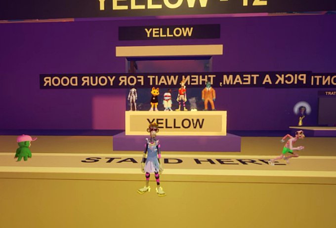 A virtual 3D environment displays the text 'YELLOW - 12' with reverse-text instructions reading 'PICK A TEAM, THEY WAIT FOR YOUR DOOR', featuring a character standing on a 'STAND HERE' mark.
