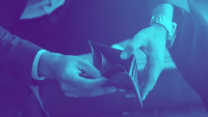 A close-up, blue-tinted photograph of a person's hands holding and opening a brown paper origami fortune teller (cootie catcher).