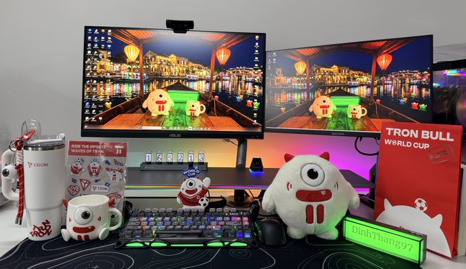 A crypto trader's dual-monitor setup decorated with TRON and World Cup merchandise, featuring a 'Ride the Wave, Make the World Cup' display.