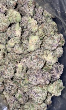 A bag of dense, purple-tinged cannabis buds is shown, with the post joking about paying $50 for a "zip" (ounce) by 2026. The image humorously reflects frustration over rising cannabis prices through the visual of premium-quality flower.